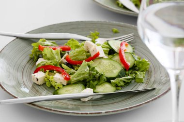 Restorandaki masada taze Yunan salatası ve bir bardak içecek.