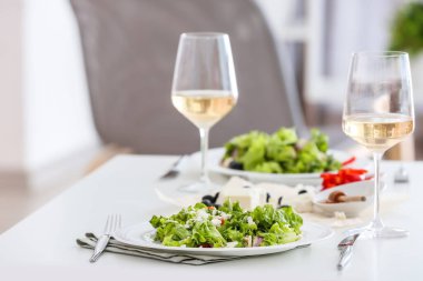 Restorandaki masada taze Yunan salatası ve bir bardak şarap.