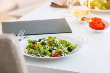 Restorandaki masada taze Yunan salatası ve bir bardak şarap.
