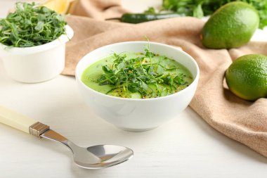 Yeşil gazpacho ve hafif arka planda malzemelerle dolu bir kase.