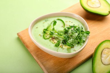 Renk arkaplanında yeşil gazpacho ve avokado olan tahta