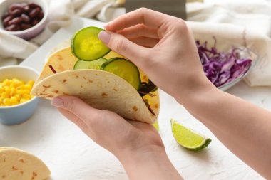 Kadın arka planda lezzetli taco yapıyor, yakın plan.