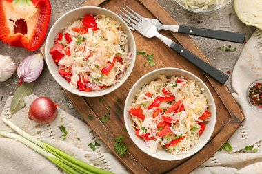 Lezzetli lahana turşulu kaseler ve arkaplandaki malzemeler.