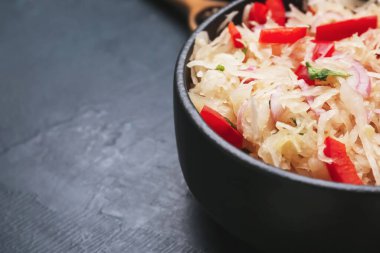 Koyu arkaplanda lezzetli lahana turşusu olan bir kase, yakın plan.