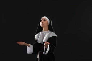 Karanlık arka planda dua eden genç rahibe.