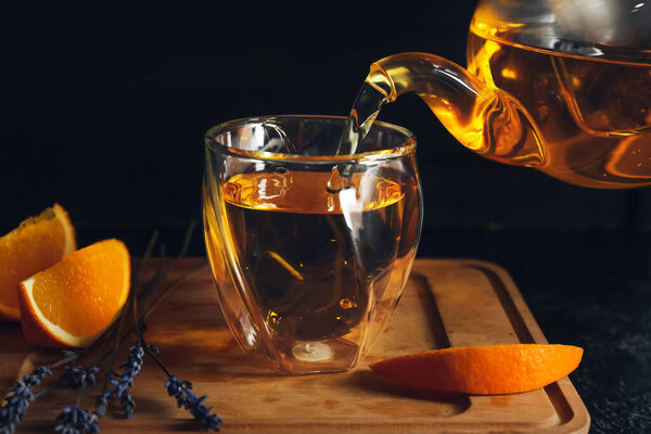 Pouring of hot tea in glass on table