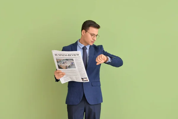 Ung Affärsman Med Tidningen Tittar Armbandsur Färg Bakgrund — Stockfoto