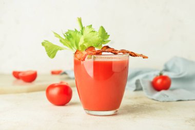 Domuz pastırması ve domateslerle süslenmiş bir bardak Bloody Mary kokteyli.