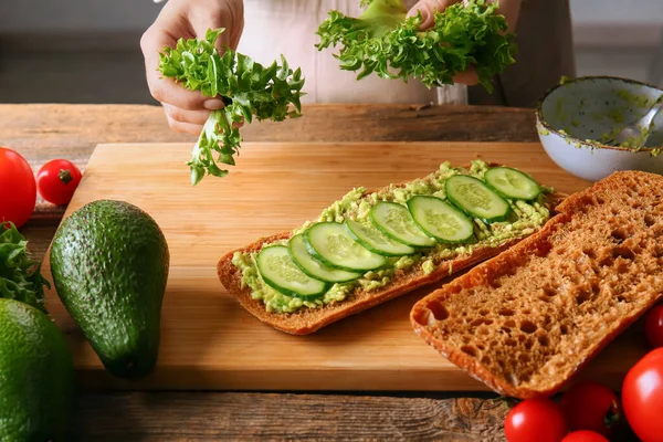 Vrouw Bereidt Smakelijke Sandwich Houten Achtergrond — Stockfoto