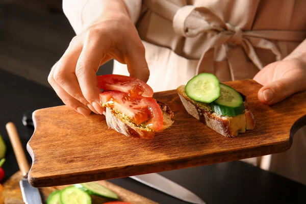 Woman holding board with tasty sandwiches, closeup