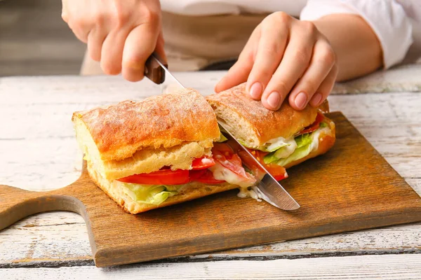 Woman Cutting Tasty Sandwich Light Wooden Background — Stock Photo, Image