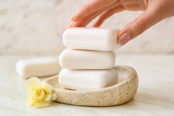 Female hand with soap bars on light background, closeup