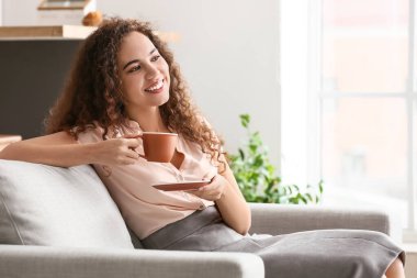 Güzel genç bayan evde kahve içiyor.