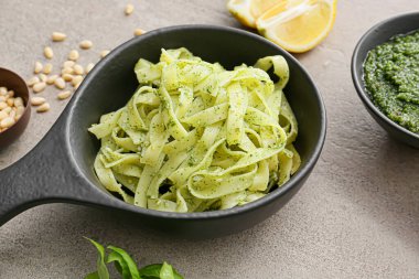 Gri arka planda pesto soslu lezzetli makarna.