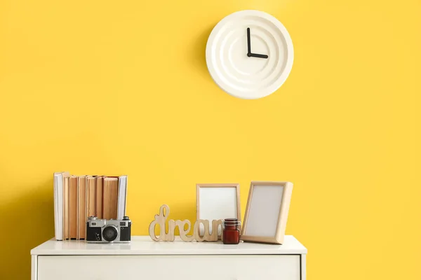Συρταριέρα Βιβλία Και Διακόσμηση Κοντά Κίτρινο Τοίχο Στο Εσωτερικό Του — Φωτογραφία Αρχείου
