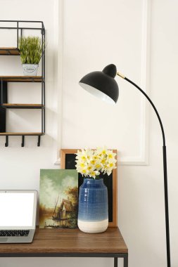 Narcissus çiçekleri ve dizüstü bilgisayarı olan bir vazo.