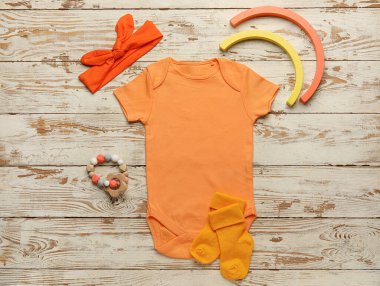 Hafif ahşap arka planda bebek kıyafetleri ve aksesuarlar.