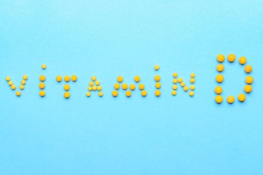 Renk arkaplanındaki haplardan yapılmış VITAMIN D metni