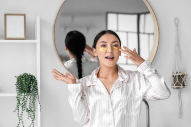 Güzel Asyalı kadın banyoya göz altı bantları yapıştırıyor.