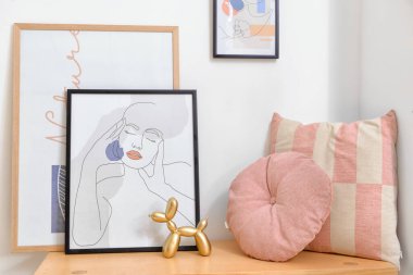 Işık duvarının yanındaki bankta resimler ve yastıklar var.