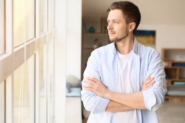 Evde pencerenin yanında yakışıklı bir adam var.