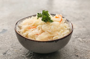 Arkaplanda lezzetli lahana turşusu olan bir kase.