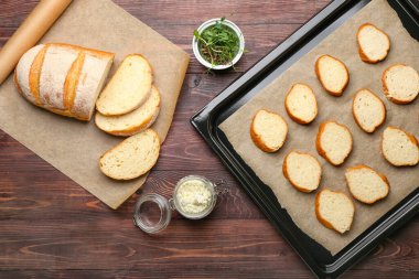 Ahşap zemin üzerinde taze ekmek dilimleri ile pişirme çarşafı