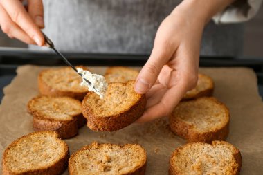 Kadın aşçı, mutfak masasında peynirli tost hazırlıyor.