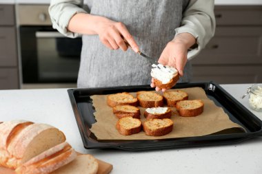 Kadın aşçı, mutfak masasında peynirli tost hazırlıyor.