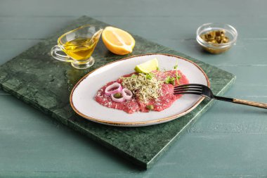 Lezzetli dana carpaccio, limon ve yağlı tabak.