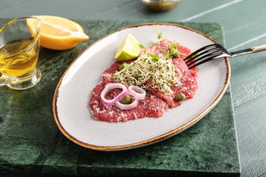Lezzetli dana carpaccio, limon ve yağlı tabak.