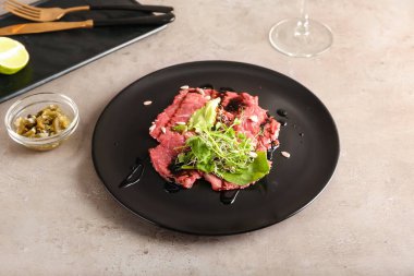 Lezzetli dana carpaccio tabağı ve grunge arka planda konserve jalapeno.