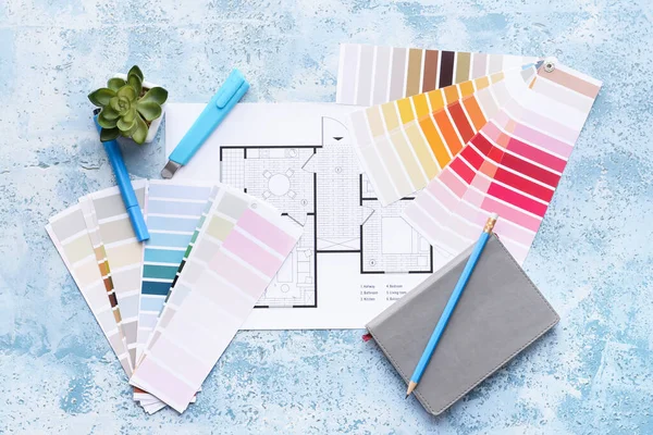 Paint color samples with house plan and notebook on color background