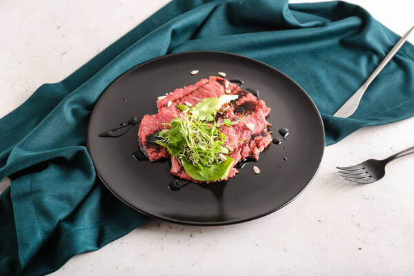 Plate with tasty veal carpaccio on light background