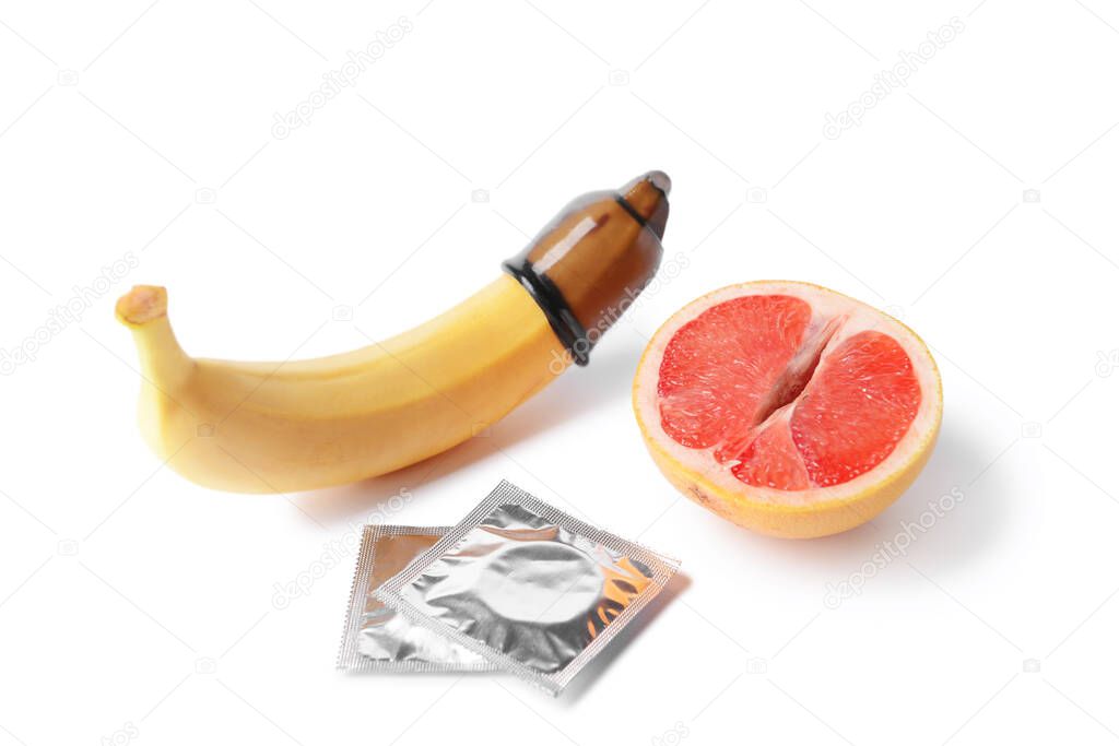 Banana and grapefruit with condoms on white background. Erotic concept