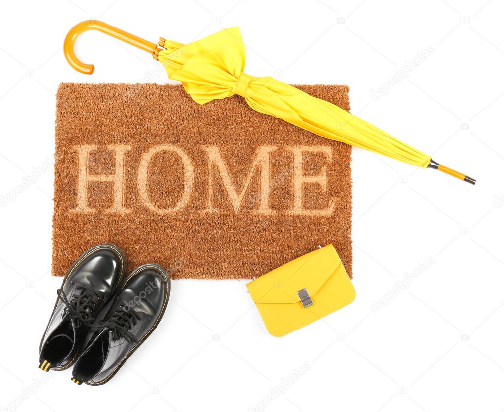 Doormat with bag, shoes and umbrella on white background