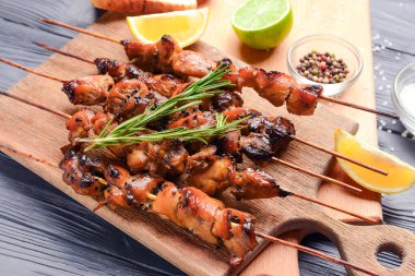 Koyu ahşap arka planda lezzetli tavuk kebabı olan bir tahta.