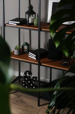 Gri duvarın yanında dekorlu şık bir kitap rafı.