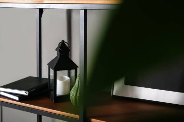 Gri duvarın yanında mum bulunan şık bir kitap rafı.