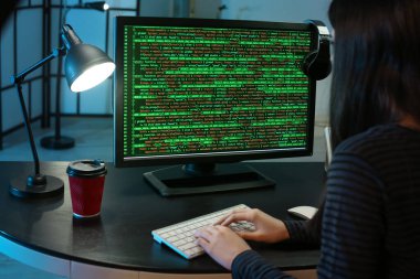 Geceleri bilgisayarla çalışan kadın programcı.