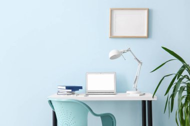 Renk duvarının yanında dizüstü bilgisayarı olan modern işyeri