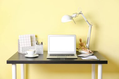 Renk duvarının yanında dizüstü bilgisayarı olan modern işyeri