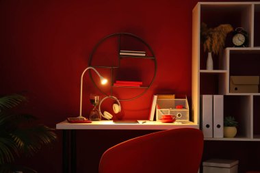 Tablet bilgisayarı ve renkli duvarın yanında parlayan lambası olan modern iş yeri