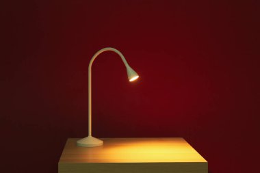 Karanlık odadaki masada parlayan lamba.