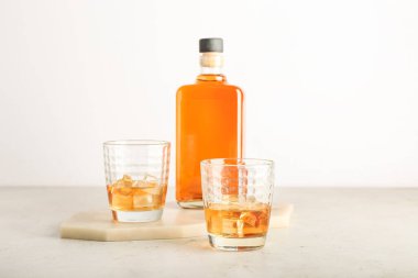 Hafif arka planda şişe ve bir bardak soğuk viski.