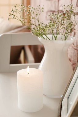 Odasında çiçekler olan yanan mum ve vazo.