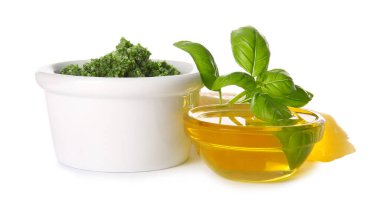 Taze pesto soslu kase, fesleğen yaprağı ve beyaz arka planda yağ.