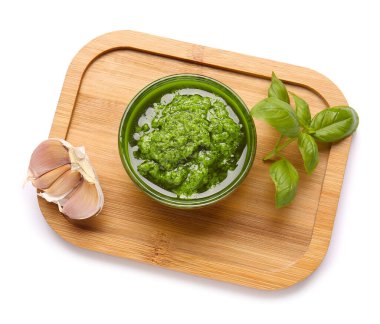 Taze pesto soslu kase, fesleğen yaprakları ve beyaz arka planda sarımsak.