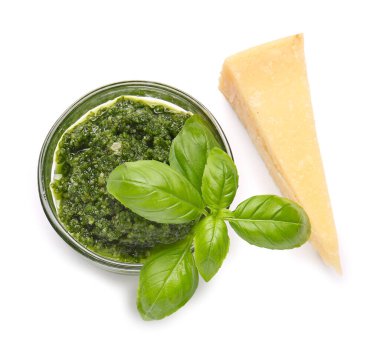 Taze pesto soslu kase, beyaz arka planda fesleğen yaprağı ve peynir.