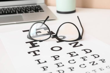 Masada göz testi çizelgesi olan şık gözlükler, yakın plan.